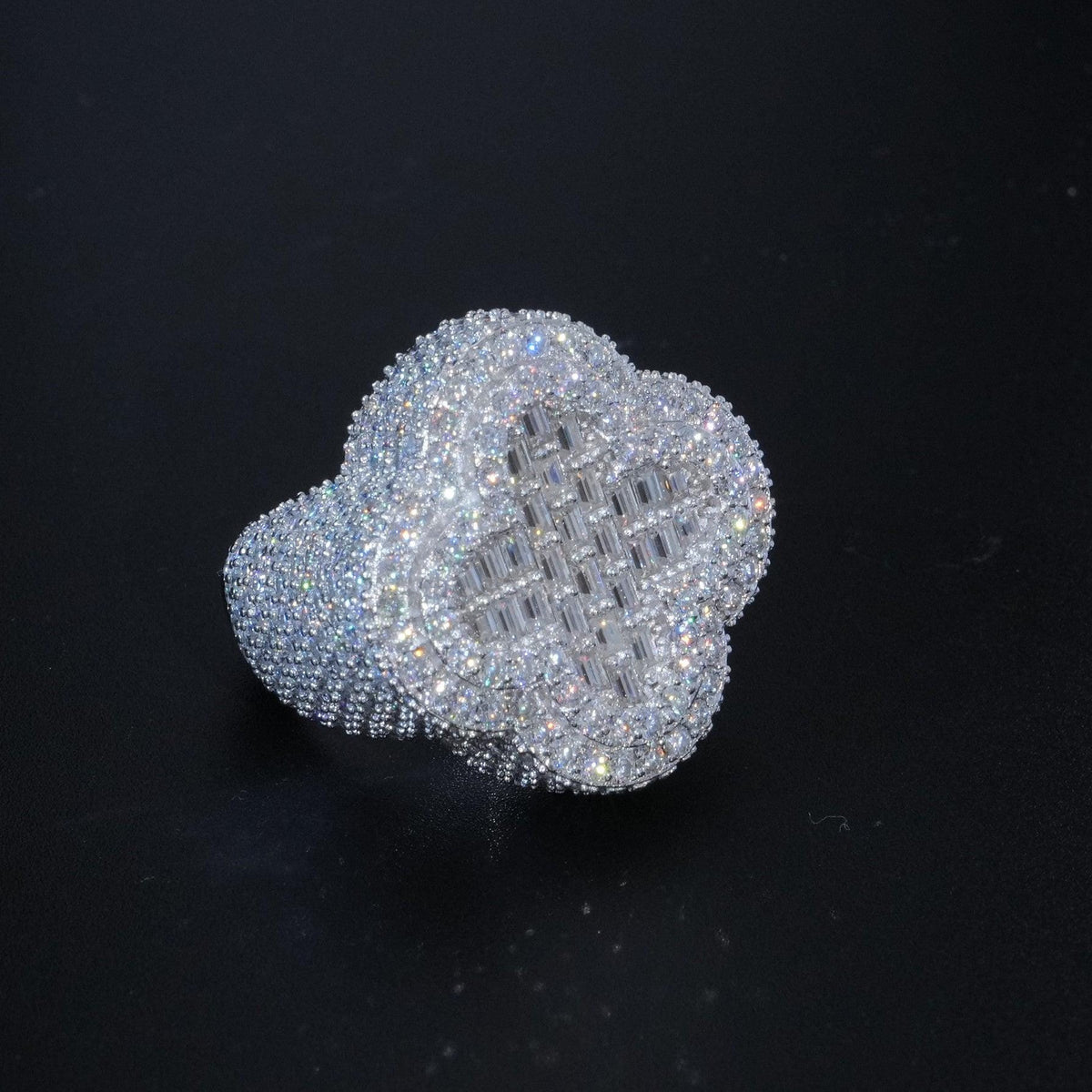 May include: A silver ring with a large, clear, cubic zirconia stone in the center. The stone is surrounded by smaller, clear, cubic zirconia stones. The ring is designed in a clover shape.