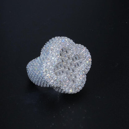 May include: A silver ring with a large, clear, cubic zirconia stone in the center. The stone is surrounded by smaller, clear, cubic zirconia stones. The ring is designed in a clover shape.