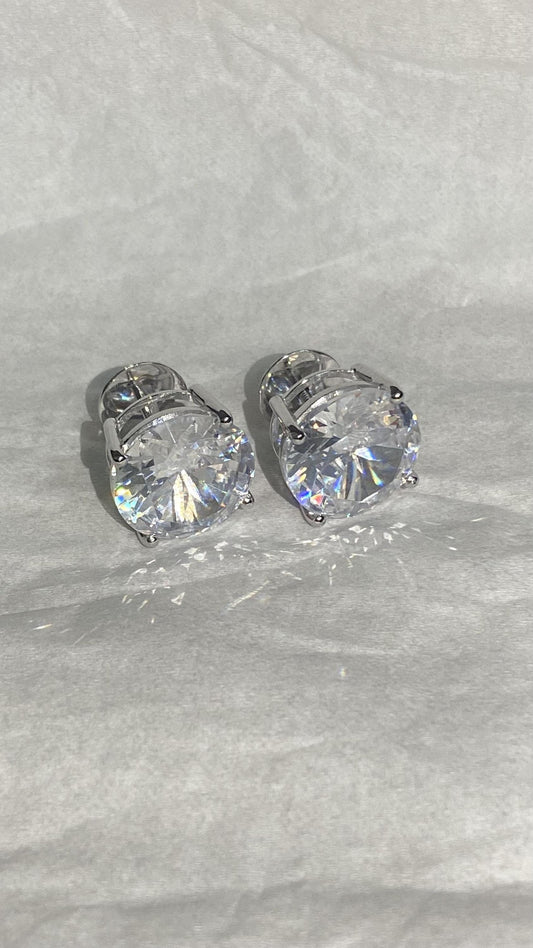 May include: A pair of silver earrings with large, clear, round cubic zirconia stones.